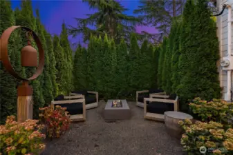 Another view of the private garden space highlights the cozy firepit surrounded by evergreens.