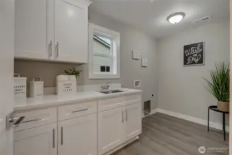 The upstairs laundry balances efficiency and elegance, with built-in storage cabinets and a sink to make household tasks a seamless part of modern living.