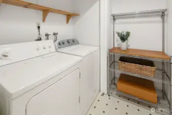 Laundry room sits just off primary suite and also offers storage space.