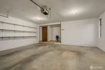 Ample 2 car garage with storage shelves and storage area.
