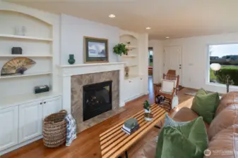 Main entry area/living room features a fireplace, built-in bookshelves, and expansive windows overlooking both the front and back yards.