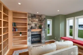 Library with fireplace, window seat, and floor-to-ceiling maple built-in bookshelves with entertainment space.