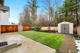 Entertaining sized backyard with long patio for  family gatherings, bricks on surrounding walking path, outdoor shed for storage, designated for gardening.