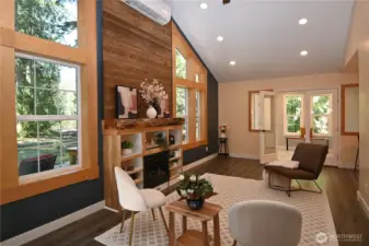 Vaulted ceilings soar above a gas fireplace with custom wood mantel, wrapped windows, and a warm floor-to-ceiling wood wall feature ~ crafted from timber sourced on the property ~ create a true standout living space.