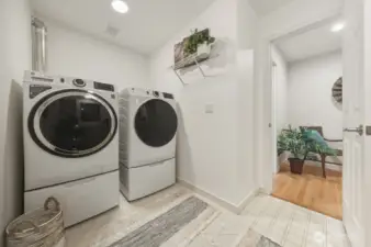 To the left of the main-floor powder room, a spacious utility room offers generous space for laundry and more. To the right (not shown), a convenient sink, expansive counterspace, and additional storage await.