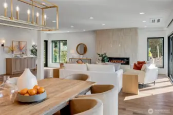 This true great room flows seamlessly from the kitchen into the family room, where a sleek modern fireplace creates a warm and inviting anchor for the space. The open layout is bright, comfortable and perfect for gathering, with easy connection to the dining area and outdoor living.