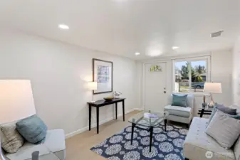 A comfortable lower-level family room with new LVP flooring, recessed lighting, and a flexible layout well suited for lounging, media, guests, or play, with direct exterior access to the front driveway.