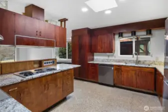 Equipped with stainless steel appliances, terrazzo floors, rich cabinetry, and a window above the sink, the kitchen is both stylish and functional.