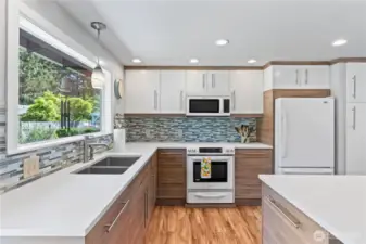 Abundant natural light floods this thoughtfully designed kitchen, highlighting the dual-tone cabinetry, sleek hardware, and full tile backsplash.