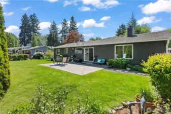 Enjoy seamless indoor-outdoor living with this beautifully maintained backyard featuring a generous concrete patio, ideal for summer BBQs and family gatherings. Surrounded by mature landscaping and privacy trees, this level yard offers ample green space for kids, pets, and entertaining under the Pacific Northwest sky.