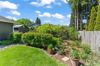 Charming garden corner with lush greenery, ornamental grasses, and decorative crane sculptures—adding a whimsical and tranquil accent to the landscaped backyard.