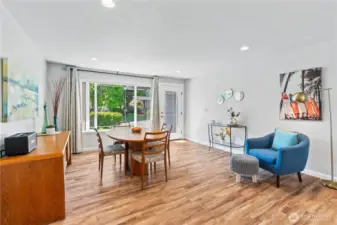 Sun-filled dining area framed by a large picture window and glass door, offering lush front yard views and direct access to the patio—perfect for entertaining or everyday meals.