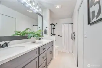 The primary bathroom offers double sinks with granite countertops and a walk-in shower, complemented by ample cabinet storage.