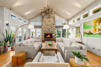 Living room with soaring ceilings is anchored by a Montana Glacier Stone wood burning fireplace and hearth.