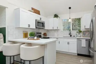 Beautiful quartz countertops on breakfast bar, white cabinets & SS appliances in kitchen. Nice!