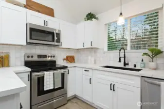 Another view of kitchen with range, microwave, deep kitchen sink, dishwasher.