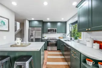 Cool modern kitchen includes wood shaker-style cabinets, quartz counters, stainless appliances, and a window to enjoy the peaceful setting while you work.