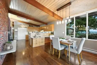 Open concept kitchen with stainless steel appliances, warm wood cabinetry, and spacious counters flows into living and dining. Tongue and groove ceilings add custom charm and cozy character throughout. Bright, airy layout perfect for entertaining or quiet mornings.