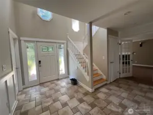 Bright foyer featuring decorative glass door, natural light, and open staircase