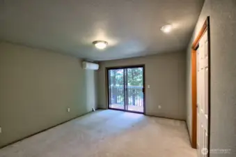 View of primary bedroom from doorway. Sliders lead to a deck overlooking the back yard and the lake.