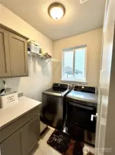 Main floor laundry room is just off kitchen, window and cabinets for storage.