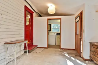 Looking back at the laundry/utility room  which houses the hot water heater, washer &  dryer & freezer. The door to the right is the  entrance for which we have put the keybox  for your broker to open the house. The red  door is to the kitchen.