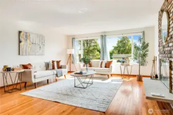 Large, east-facing windows fill the living room with morning light. Enjoy the beauty of solid oak hardwood floors installed in 2024.