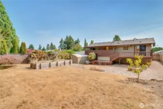 This fully fenced, terraced back yard includes open lawn, a large raised bed, a big garden shed, 6 young fruit trees, and a Japanese maple.