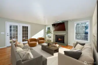 Family room with doors to fully fenced backyard and patio. Digitally staged (except for TV)