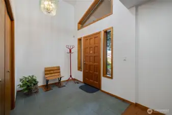 Inviting entry with soaring ceilings, warm wood accents, and abundant natural light creates an immediate sense of openness. Thoughtfully designed with clean lines and a welcoming feel, setting the tone for the home’s architectural style.