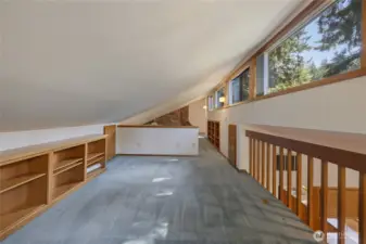 Expansive upper-level loft overlooking the main living area, featuring open railing, abundant light, and flexible space for office, media, or study.