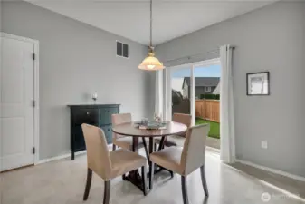 Kitchen eating nook with sliding glass door out to the side yard with patio.