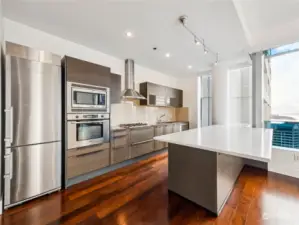 The chic kitchen features sleek stainless steel appliances, elegant slab countertops, and a stylish peninsula breakfast bar—perfect for both casual dining and entertaining.