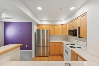 Kitchen adjacent to dining area with appliances, tile countertops and hardwood flooring
